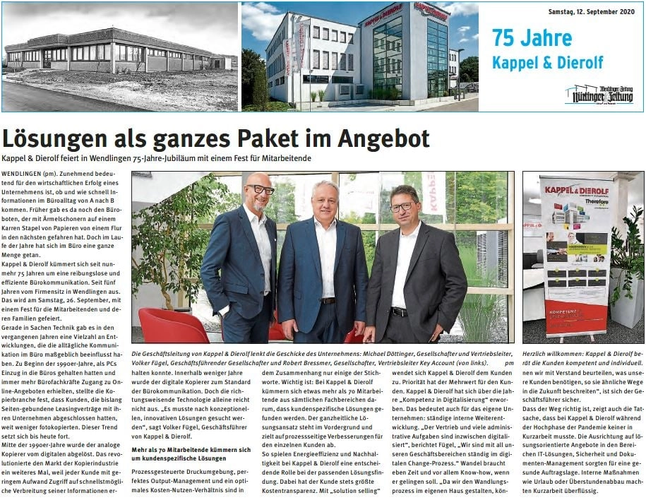 75-Jahre-KD Drei Männer stehen lächelnd vor einem Bürofenster, neben einem Roll-Up mit Kappel & Dierolf Logo, zum 75-jährigen Jubiläum.