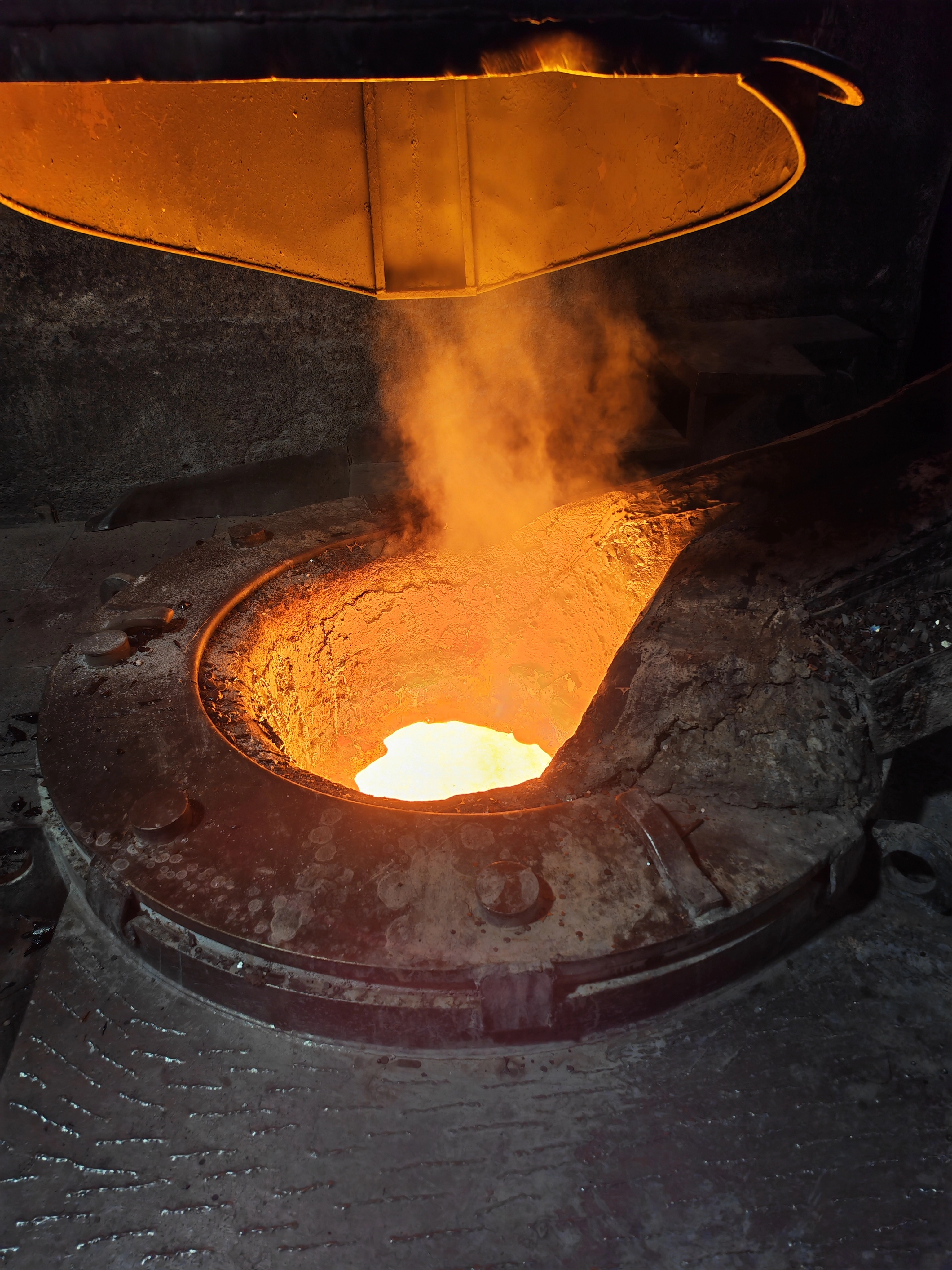 Heißer Schmelzofen mit flüssigem Metall und aufsteigendem Dampf in einer dunklen industriellen Umgebung.