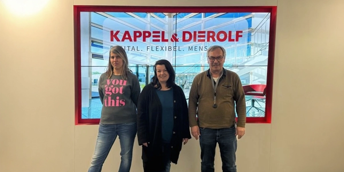 Kappel-Dierolf-Blog_Uebernahme_ANKA-Drucker_Service Drei Personen vor einem Bildschirm mit Kappel & Dierolf Logo, in einem modernen Büro.