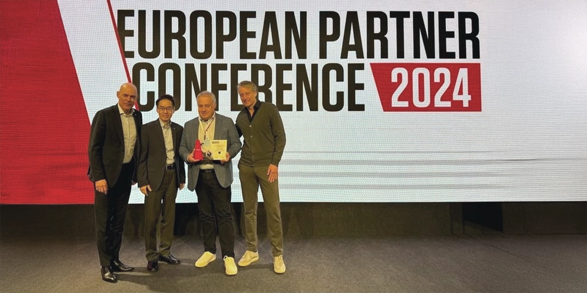 Kappel-Dierolf-Blog_halbes_Jahrhundert_Partnerschaft_Canon Vier Männer posieren vor einem Schild European Partner Conference 2024 mit einer Auszeichnung.