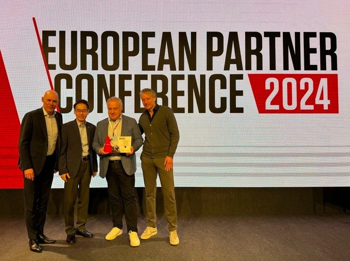 imgi_14_430073645_940320868098502_2737665852632454241_n Vier Personen posieren vor einem Schild mit der Aufschrift European Partner Conference 2024 auf einer Bühne.