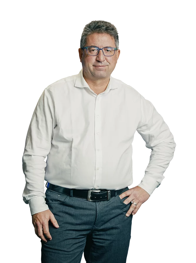 Kappel_Bressmer Ein Mann in weißem Hemd und grauer Hose steht vor weißem Hintergrund und schaut geradeaus.