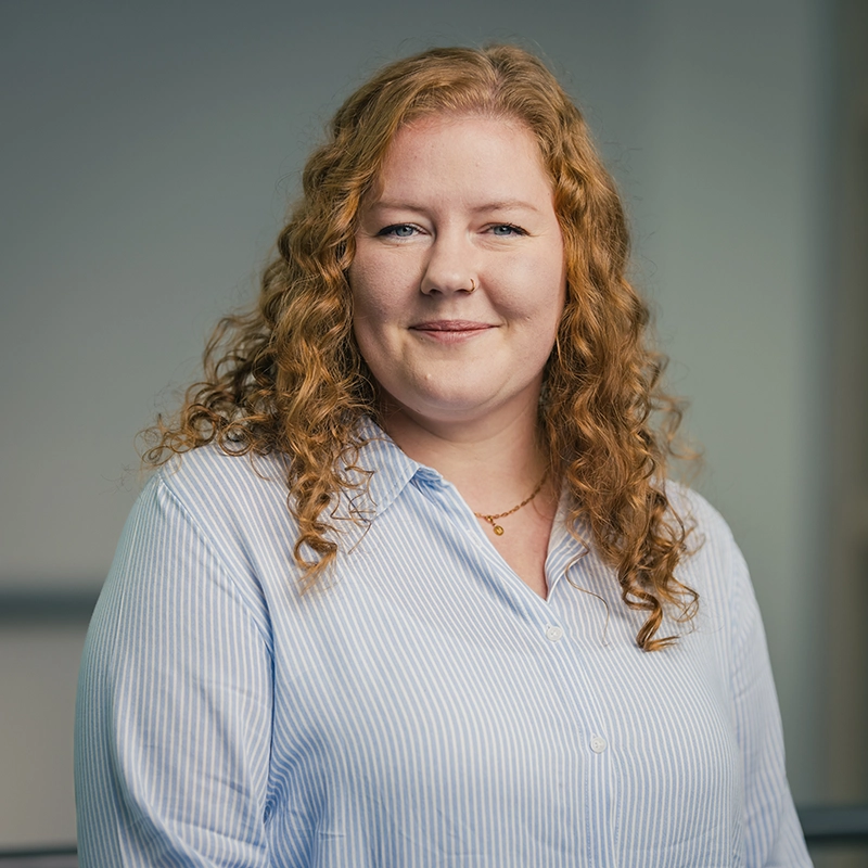 Es tut mir leid, ich weiß nicht, wer das ist.ALT-Text: Person mit lockigem Haar, lächelt in die Kamera, trägt ein hellblaues, gestreiftes Hemd.